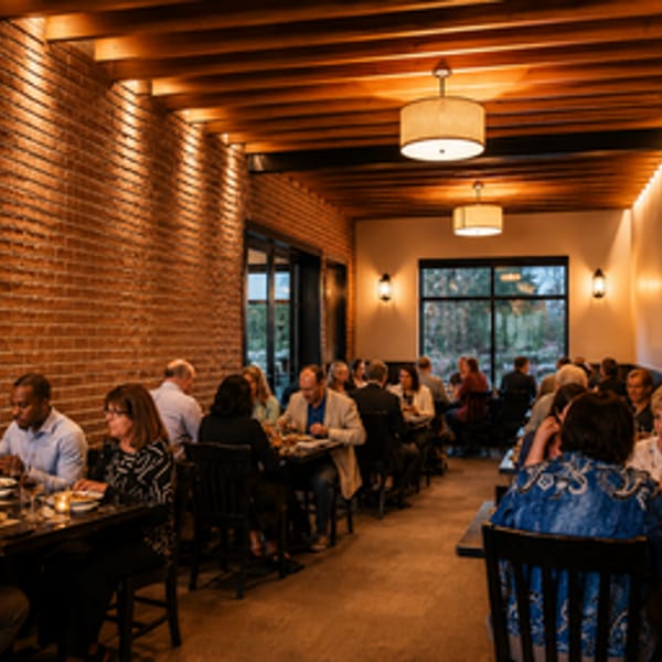 Diners enjoying meals at tables in a warmly lit restaurant with brick walls and wood ceilings.