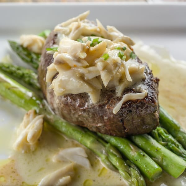 Filet mignon topped with crab meat and chives, served over asparagus with a creamy sauce.