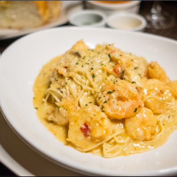 Shrimp scampi pasta with creamy sauce and parsley in a white bowl.