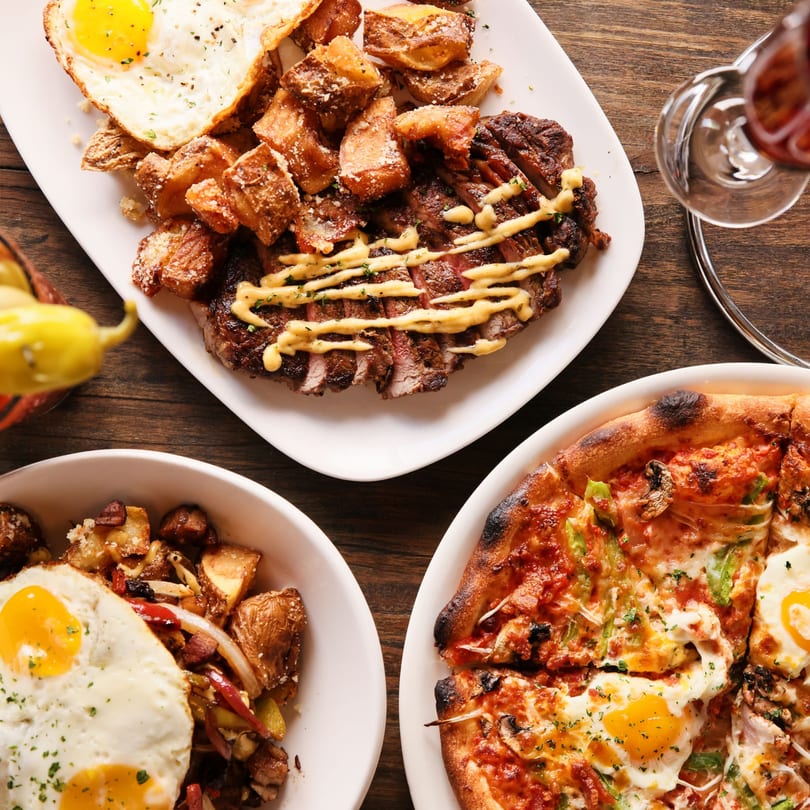 Overhead view of steak and potatoes with fried eggs, a breakfast skillet, and a pizza with eggs.