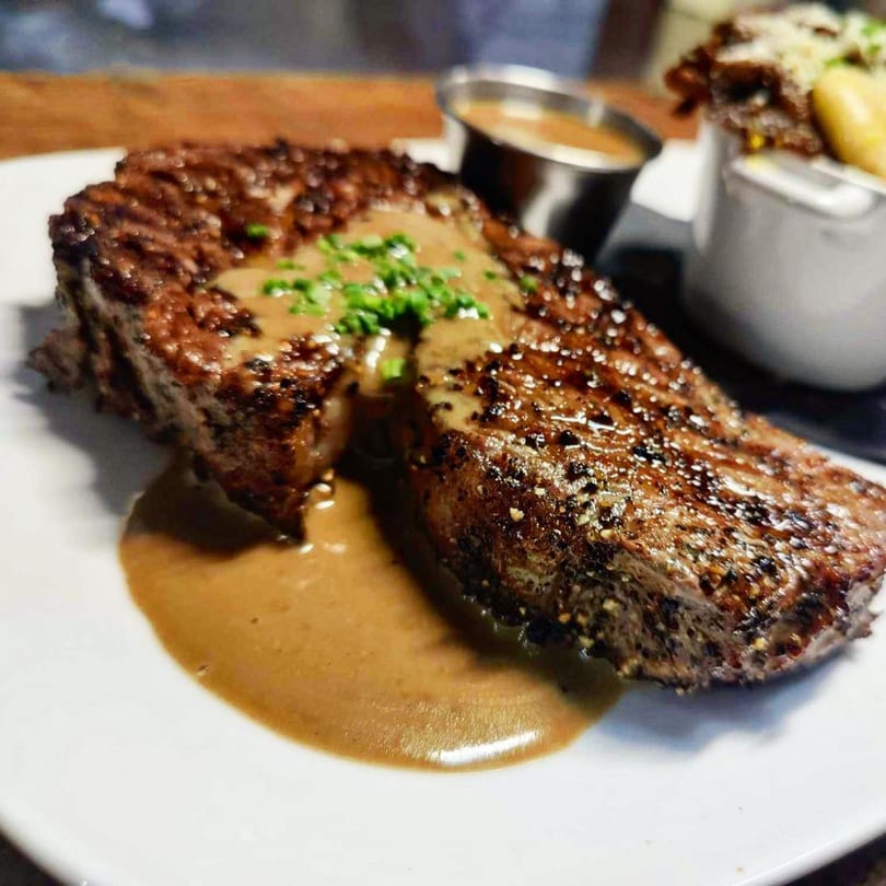 Grilled steak with sauce and chives, served with a side of fries and dipping sauce.
