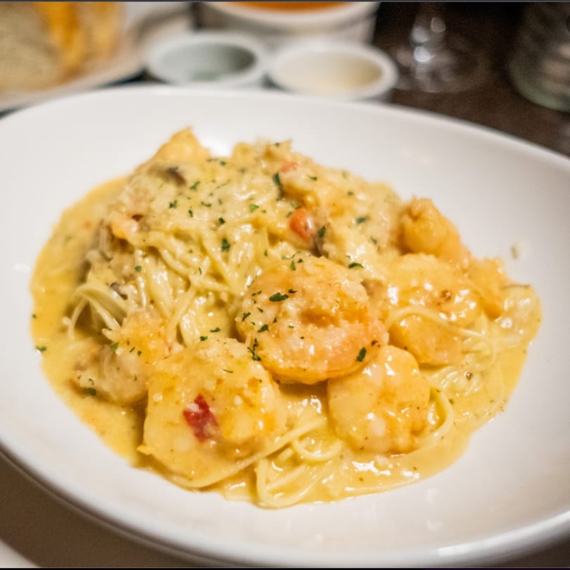 Shrimp scampi with linguine pasta in a creamy sauce, garnished with parsley, served in a white bowl.